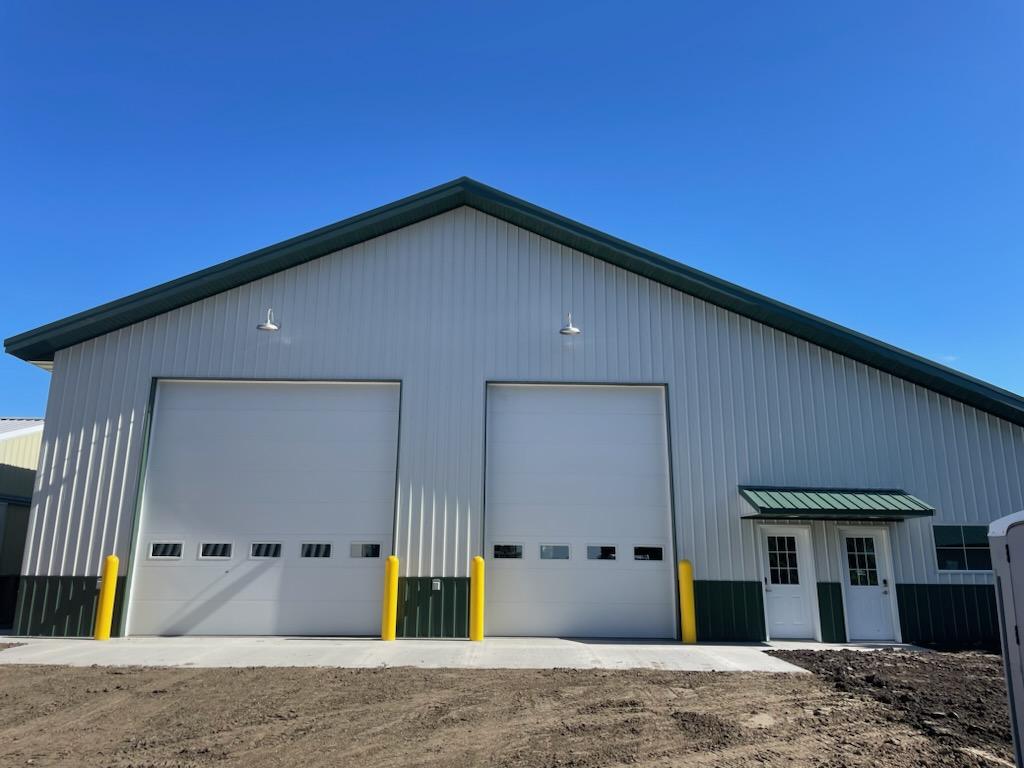 Two large overhead doors in a white and green steel building.