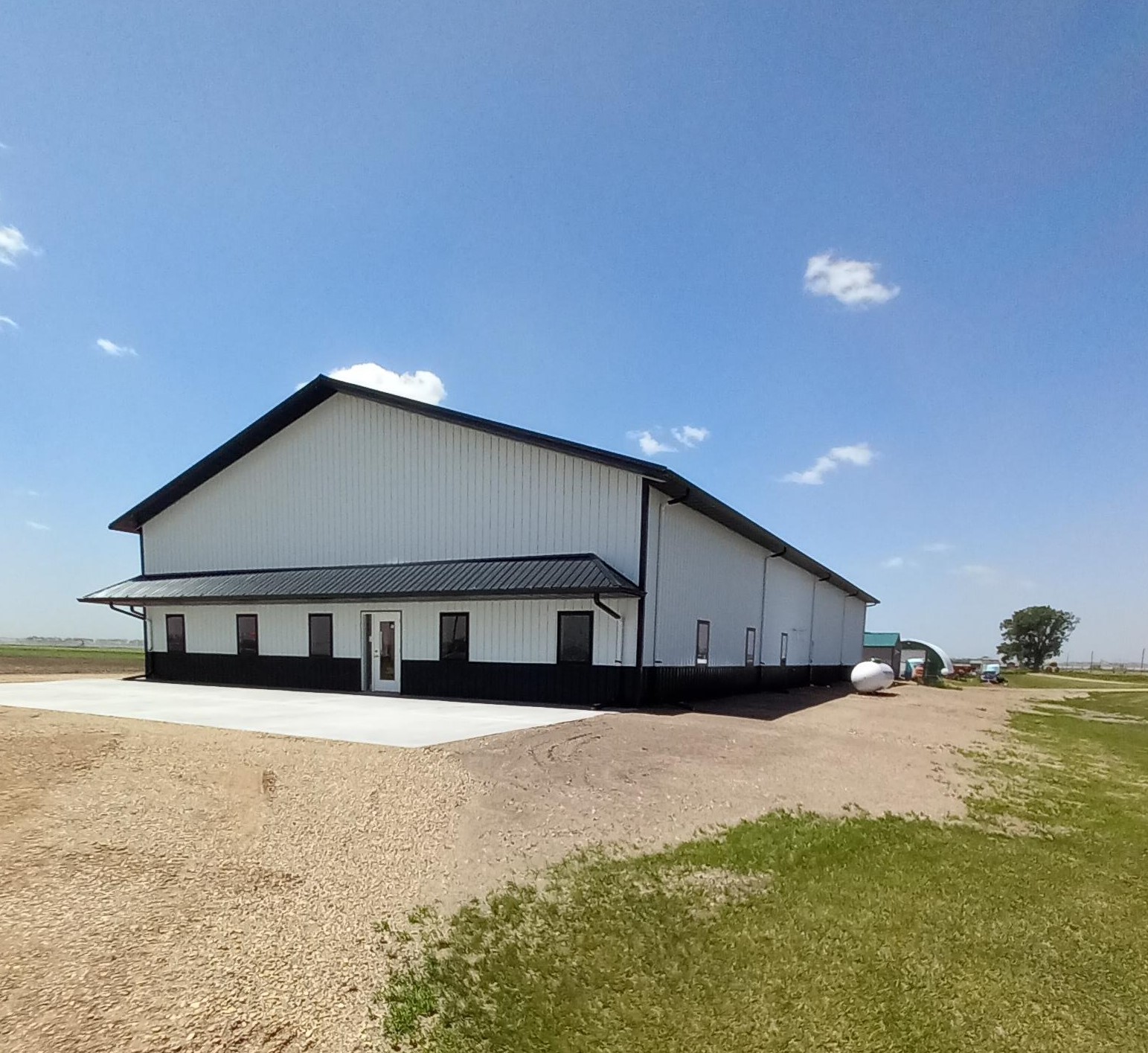 A white steel building with a black roof and wainscoting.