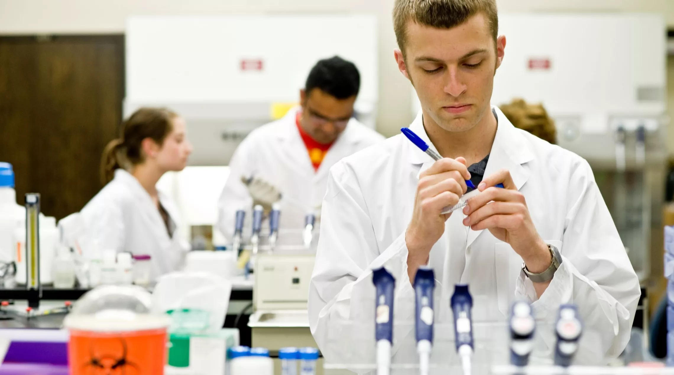 student in a lab marking a vial