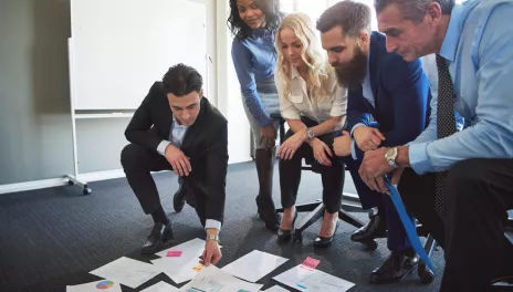 Group of people looking at papers scattered on conference room floor