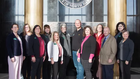 Group of people standing together under State of North Dakota seal. 