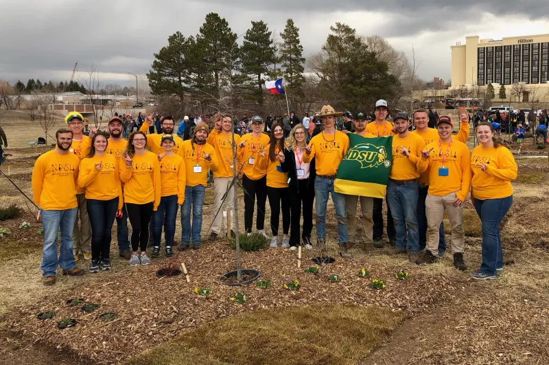 group of students in front of plant plot