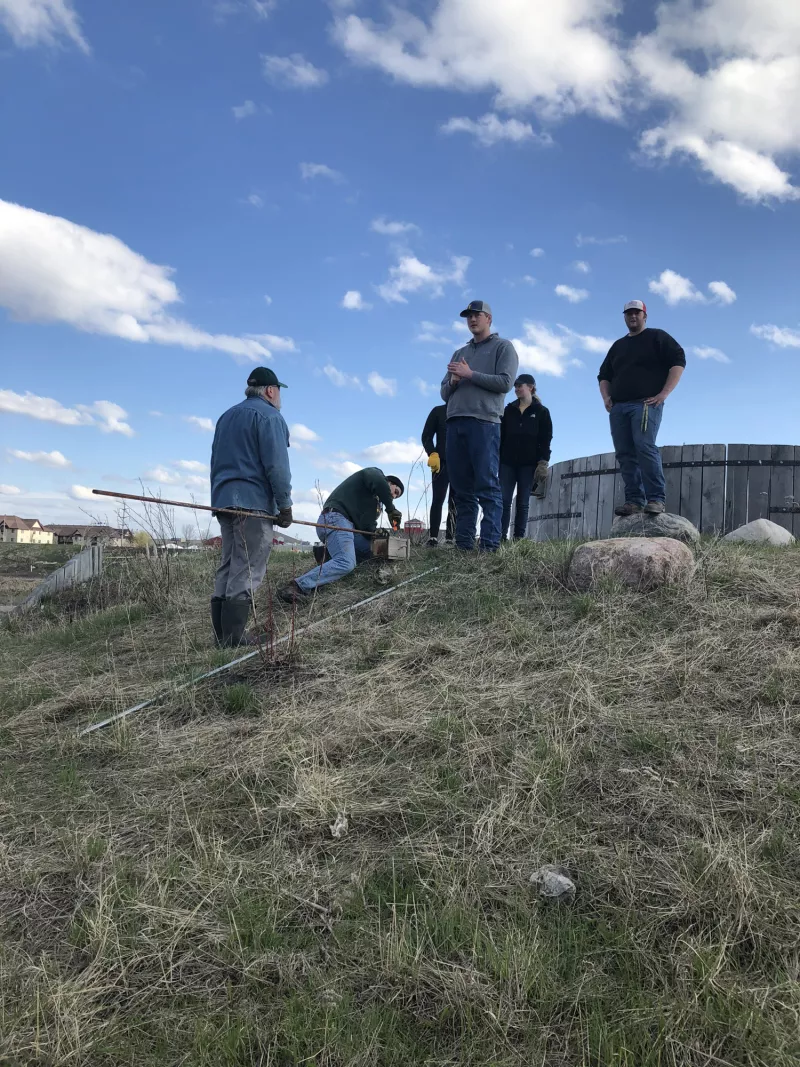 students using tools on a grassy hill