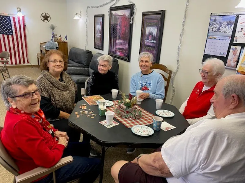 a group of senior citizens visiting around a table at Christmas