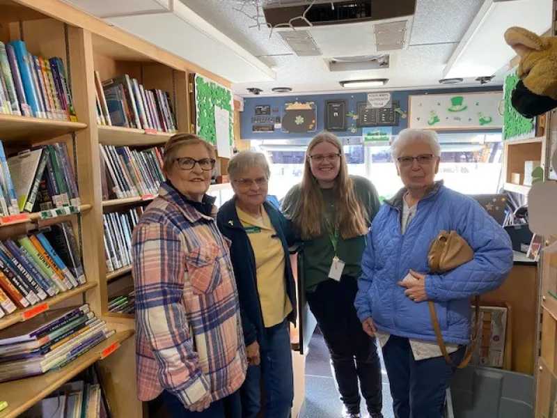 Senior citizens inside a bookmobile with shelves of books