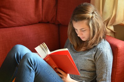 Young Adult reads book alone on couch