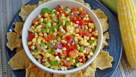 Fresh Corn Salsa, prepared and in a bowl with corn chips around it