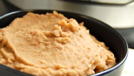 Refried Beans, served in a bowl with pressure cooker nearby