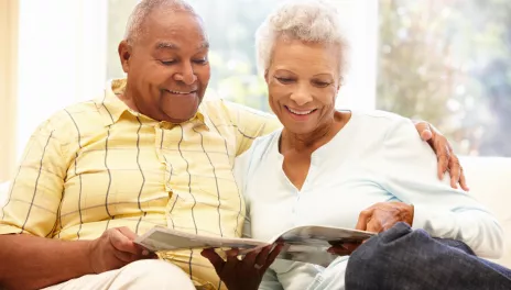 older adult couple reading magazine on couch