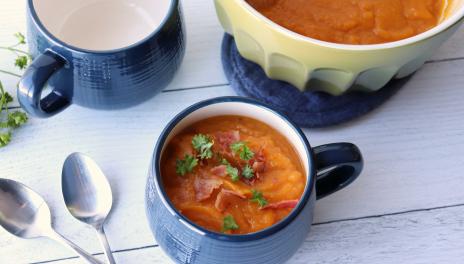 bowl of smoky sweet potato soup with bacon and parsley from larger bowl