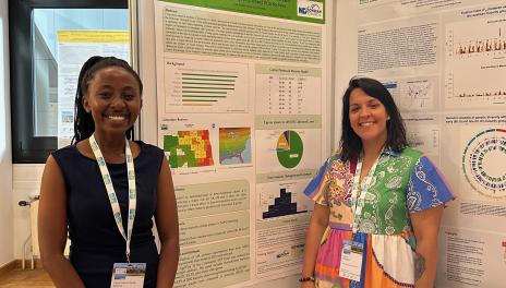 Clara Mvuta and Dr. Carrie Miranda standing in front of a research poster on genetic mechanisms of maturity.