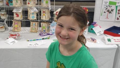Girl poses in front of projects she made in 4-H