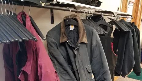 Several winter coats hang above piles of snowboots and insulated overalls