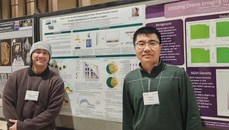 Two men standing by a poster board for plant genetics