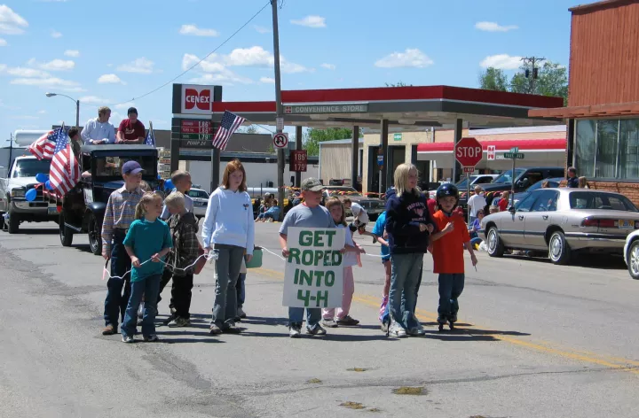 group of youth walking in a parade holding sign that reads get roped into 4-H