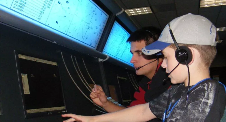 child at computer doing flight simulation with instructor