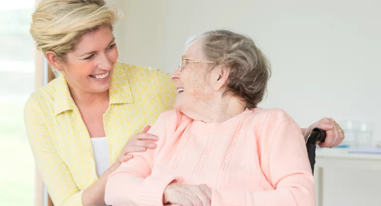 woman smiling at mom in sitting in a wheelchair