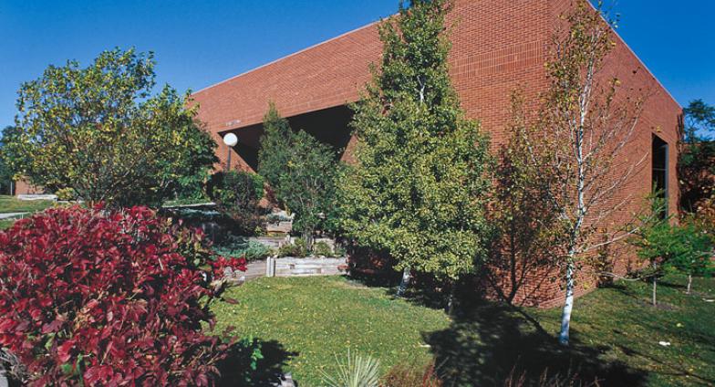 The front of Van Es Hall in summer with blue sky and trees around the building