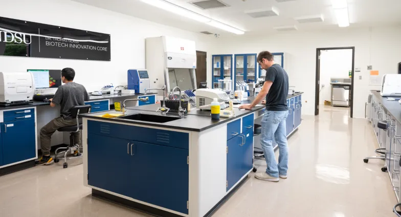 Photo of the level two lab with two researchers working at lab benches and various scientific equipment set up around the room.
