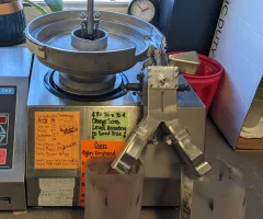 A stainless steel Seedburo counter with a vibrating metal bowl feeds kernels across electronics that count them before dumping into catch basins.